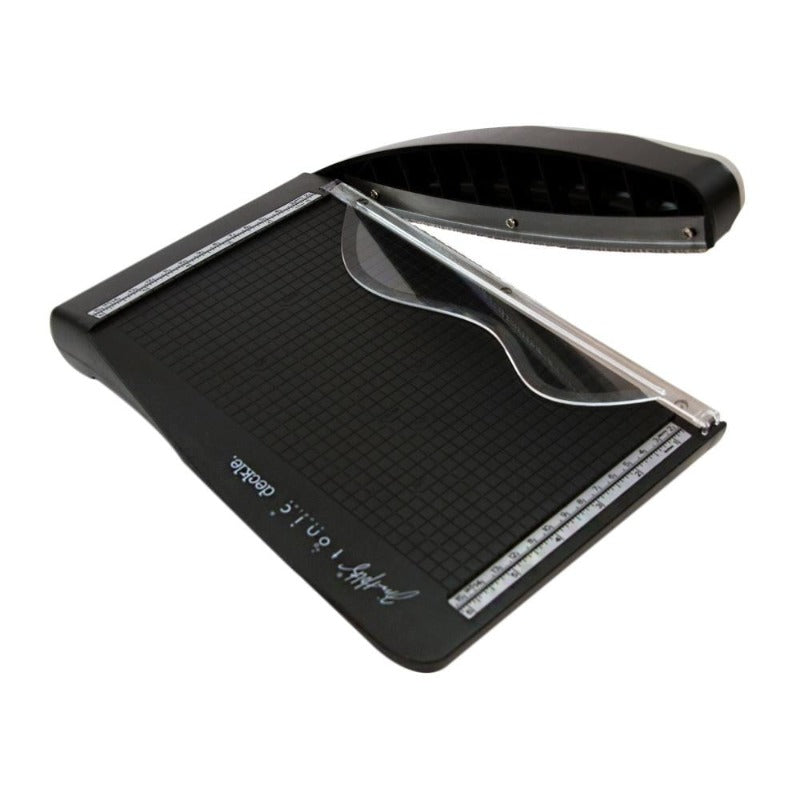 A black Tim Holtz Deckle Torn Edge Trimmer with a grid and measurements marked on the base for paper cutting.