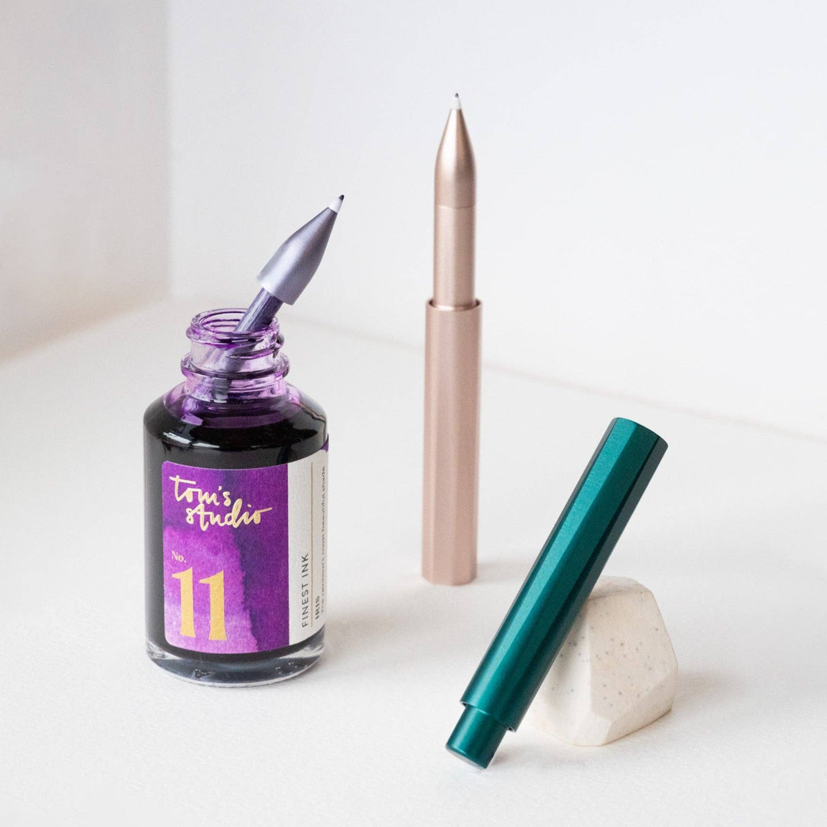 Ink bottle and two fountain pens on a white surface