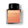 Ink bottle labeled 'Siddhartha' by Hermann Hesse with a black cap on a white background