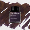 Ink bottle labeled 'The Plague' by Albert Camus on a textured brown and white background
