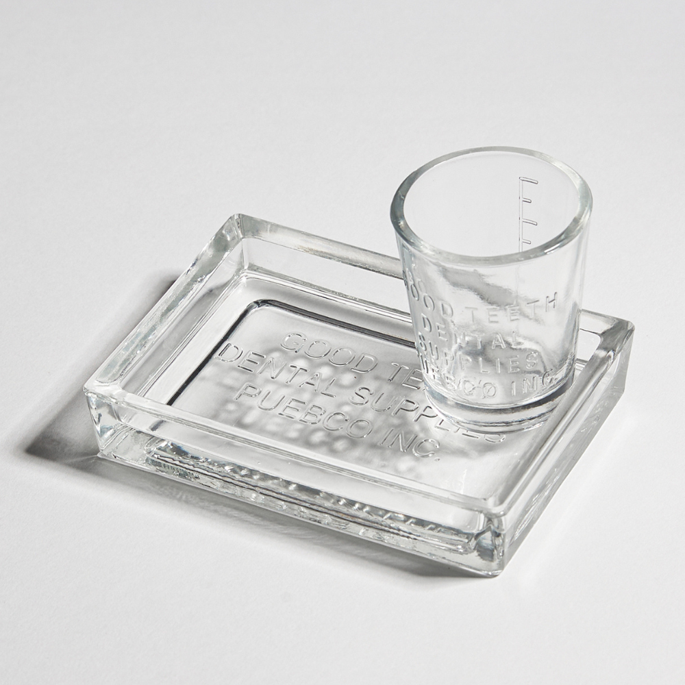 Clear glass shot glass and tray on a light gray background