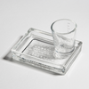 Clear glass shot glass and tray on a light gray background