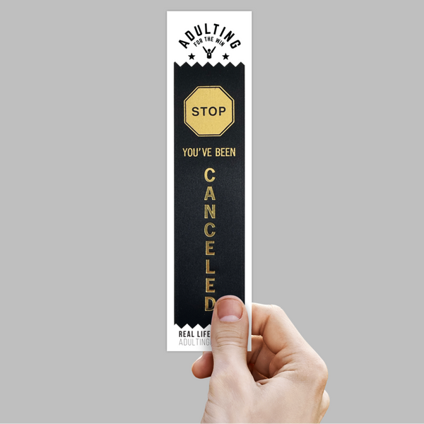 A hand holding a black award ribbon with gold foil stamp that reads 'You've Been Cancelled' in a retro style font.