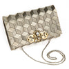 A beige handcrafted clutch bag with geometric embroidery, featuring a metallic gold thread and a chain attached to it.