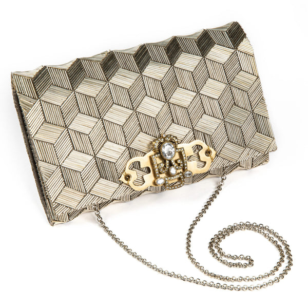 A beige handcrafted clutch bag with geometric embroidery, featuring a metallic gold thread and a chain attached to it.