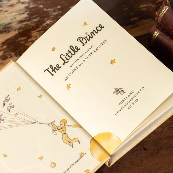 Open book of 'The Little Prince' with a wooden surface background