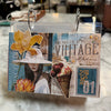 A handmade vintage-style scrapbook album or binder page with collage elements, including a yellow flower, a woman in a hat, an ice cream cone, and text like 'YOU HAD ME AT VINTAGE' and 'JAN 01', photographed hanging on a marble countertop.
