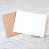 White card and brown envelope on a light wooden surface