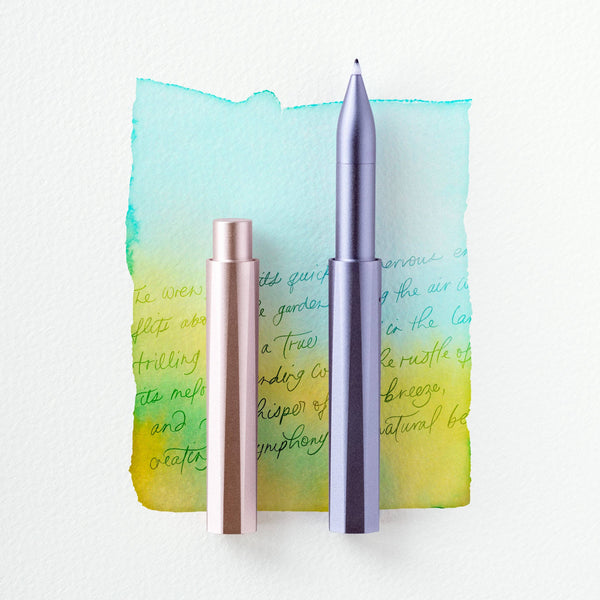 Two metallic pens on a watercolor background with text