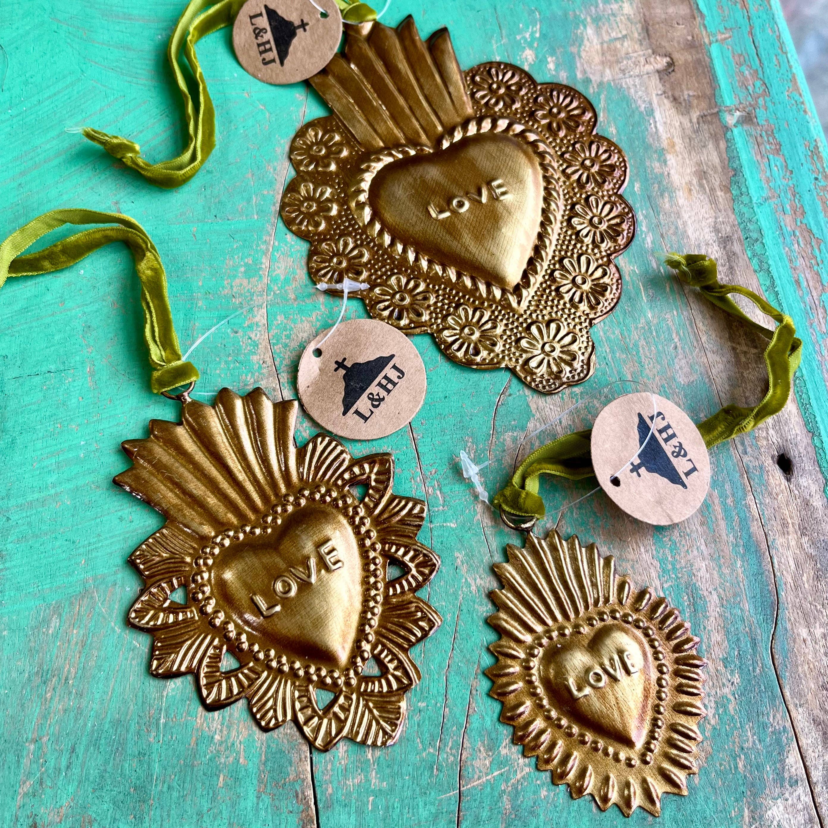 Decorative heart-shaped ornaments with 'LOVE' engraving on a teal wooden surface.