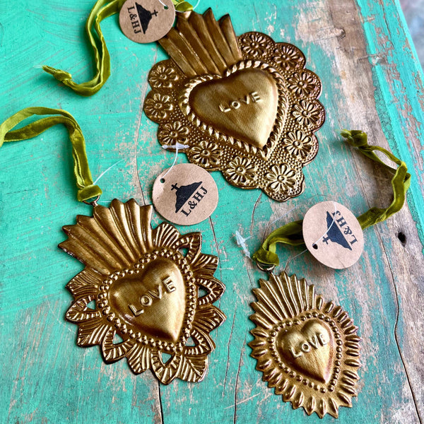 Decorative heart-shaped ornaments with 'LOVE' engraving on a teal wooden surface.