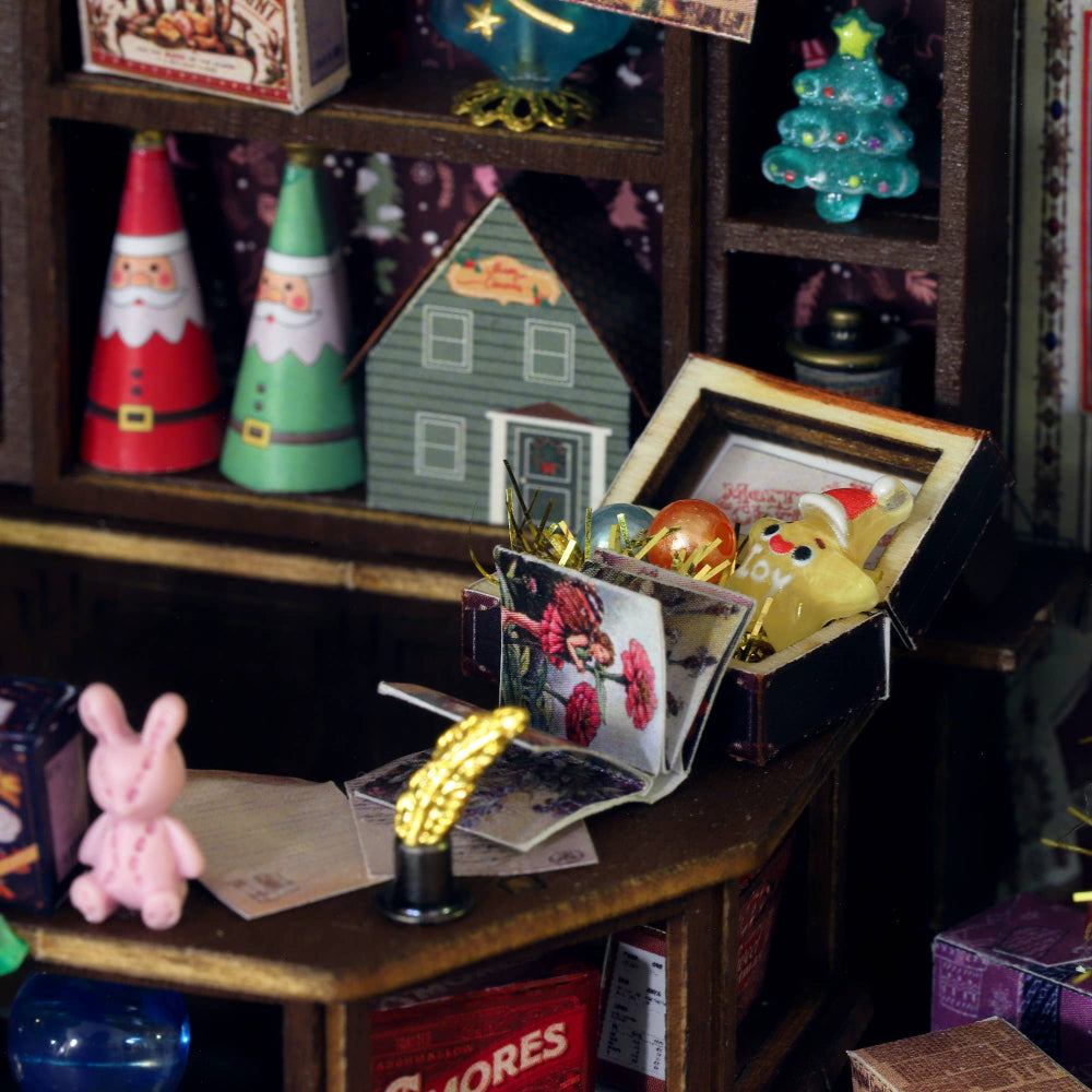 Miniature Christmas decorations on a shelf with a focus on a box containing a yellow rabbit figure.