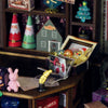 Miniature Christmas decorations on a shelf with a focus on a box containing a yellow rabbit figure.