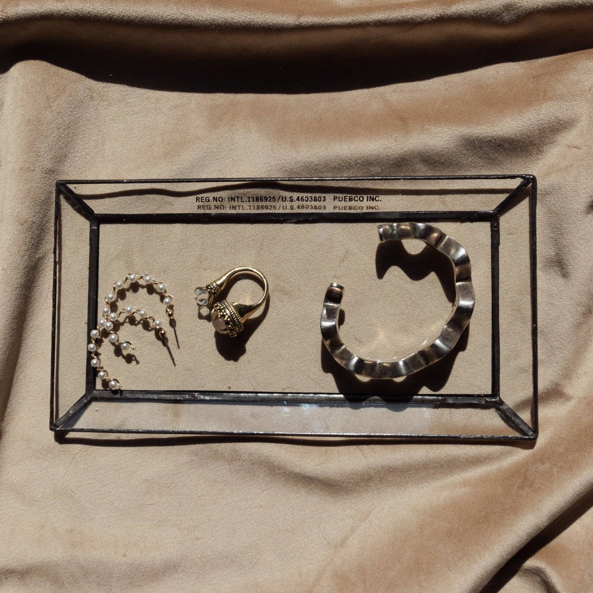 Jewelry set including a necklace, ring, and earrings displayed in a clear box on a beige fabric background.