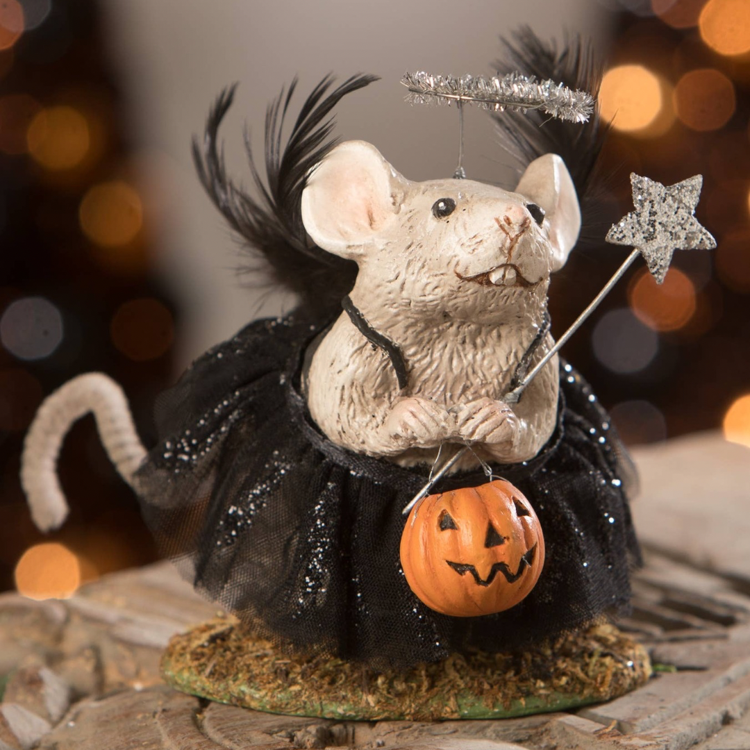 A hand-painted resin decoration featuring a mouse wearing a black dress and holding a star, with a pumpkin and black tulle details, set against a blurred holiday-themed backdrop.