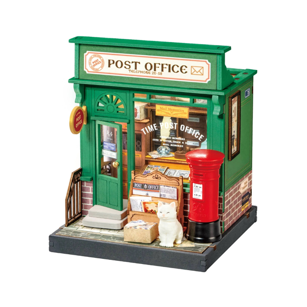 Model of a post office with a red mailbox and a cat on a white background