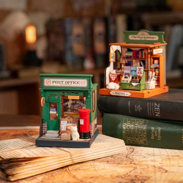 Miniature model of a post office and a bookshop on top of books with a warm, cozy background.