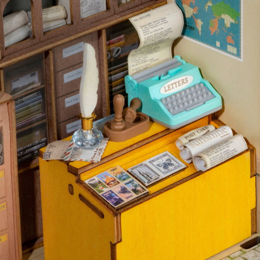 Miniature desk with typewriter, letters, and stamps in a model office setting.