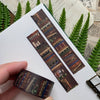 Decorative book-themed washi tape with a hand holding it, set against a textured background with greenery.