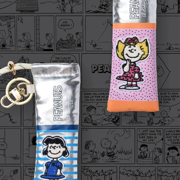 Two Peanuts-themed (Sally and Lucy) pen cases on a background with comic strip panels.