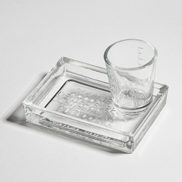 Clear glass shot glass and tray on a light gray background
